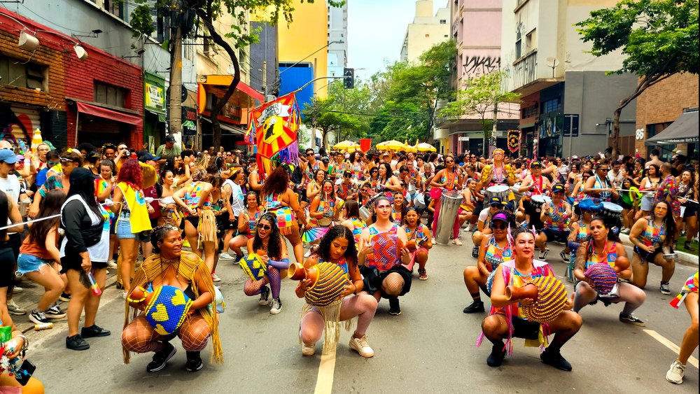 Multidão dançando ao redor da bateria do bloco Dramas de Sapatão nas ruas de São Paulo